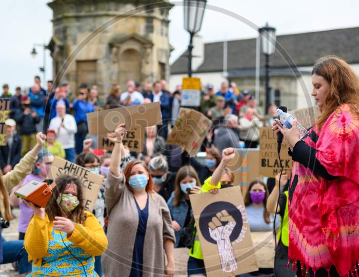 Blm Protesters Wearing Ppe Face Masks Salute And Hold Signs At Black Lives Matter Protest In Richmond, North Yorkshire