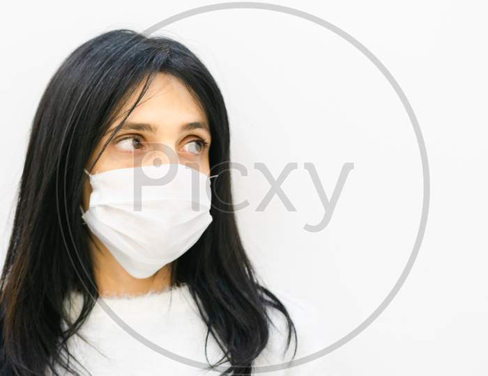 Close Up Of Young Caucasian Woman Wearing White Mask And Looking To The Right Side Of White Blank Space Area.