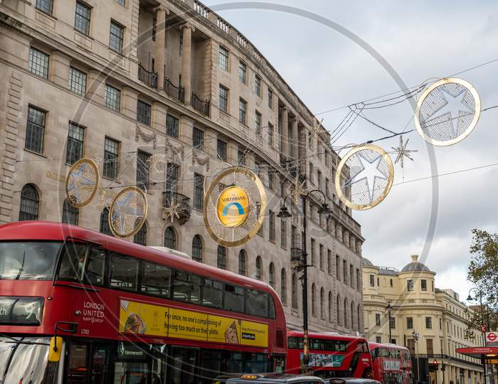 Christmas Decoration Lights Above Red London Double Decker Buses On The Strand, London