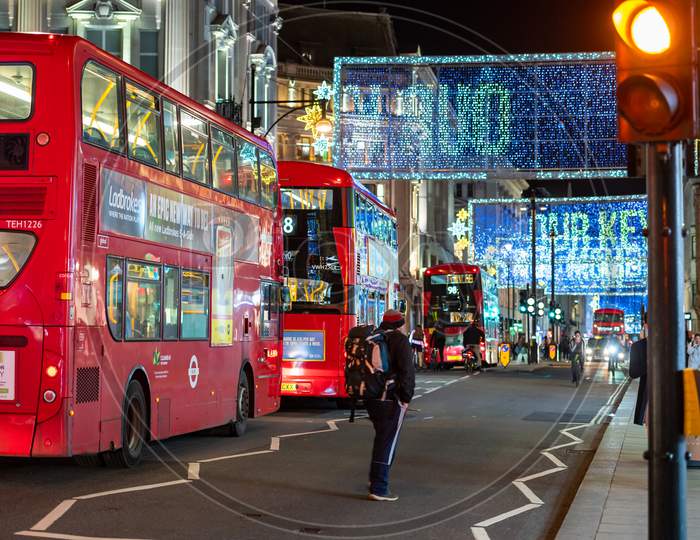 Red London Double Decker Buses With Oxford Street Illuminated Christmas Decorations In The Background