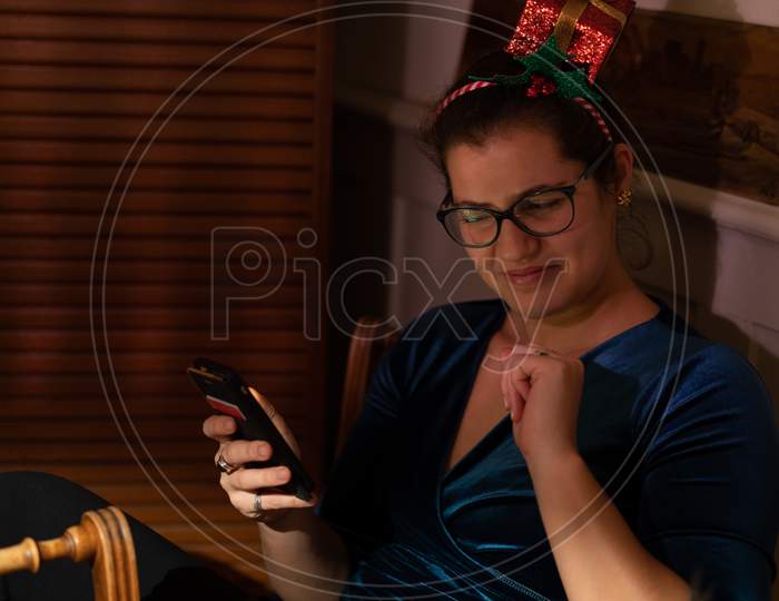 Young Woman Looking Not Amused Into Her Mobile Phone At Christmas.