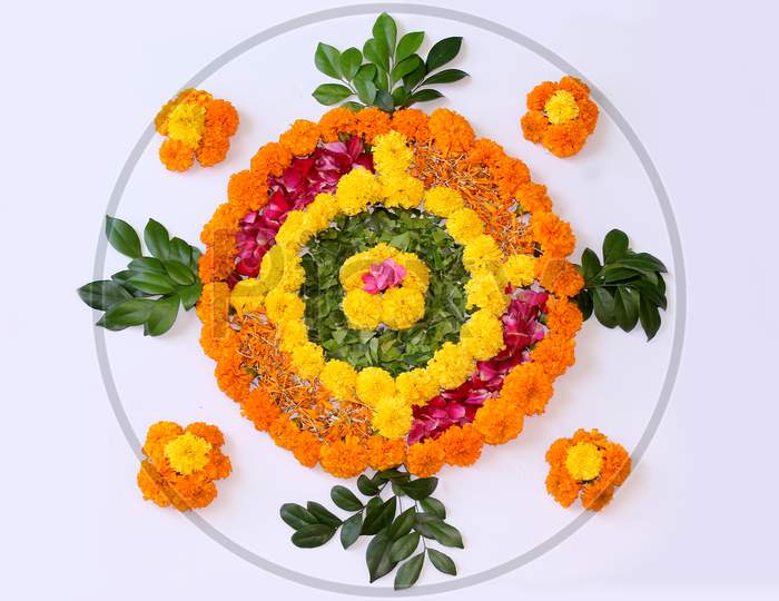 flower Rangoli for Diwali or pongal or onam made using marigold or zendu flowers and Leaves with Indian Traditional Pattern over on white background, selective focus.