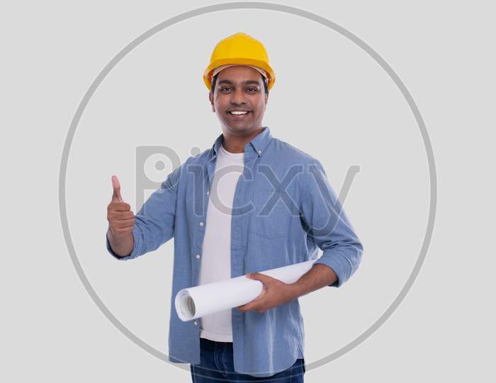 Construction Worker Holding House Plan In Hands Showing Thumb Up. Architect Holding Blueprints. Yellow Hard Helmet.