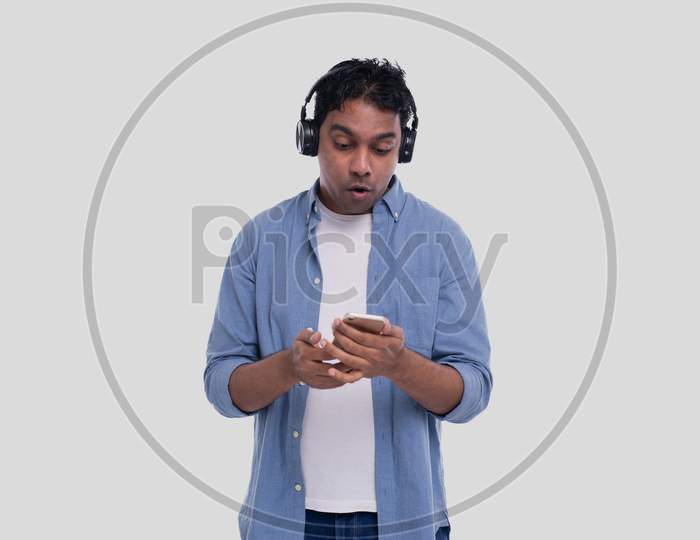 Indian Man Listening Music And Chatting On Phone Surprised. Man Is Suprised By Music From Phone. Man With Phone In Hands Isolated. Music Concept