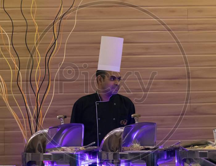 Hikkaduwa, Southern Province / Sri Lanka - 7 23 2020: Chef At The Buffet Tables With A White Chef Hat And Looking Side.