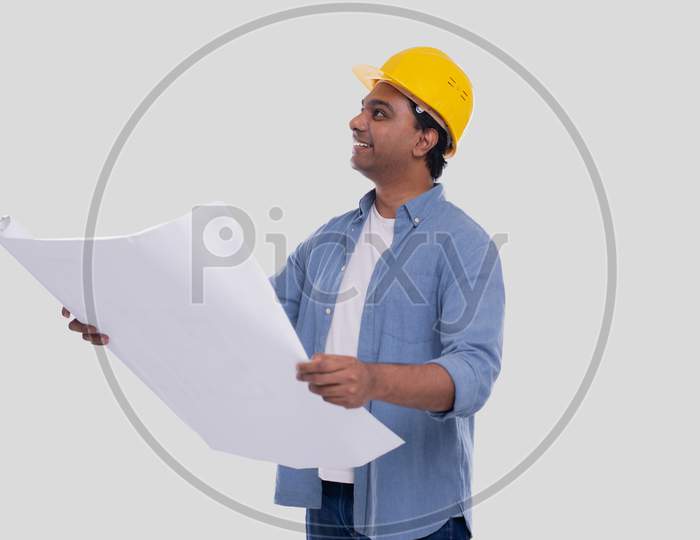 Construction Worker Holding House Plan In Hands Watching Up. Architect Holding Blueprints. Yellow Hard Helmet.