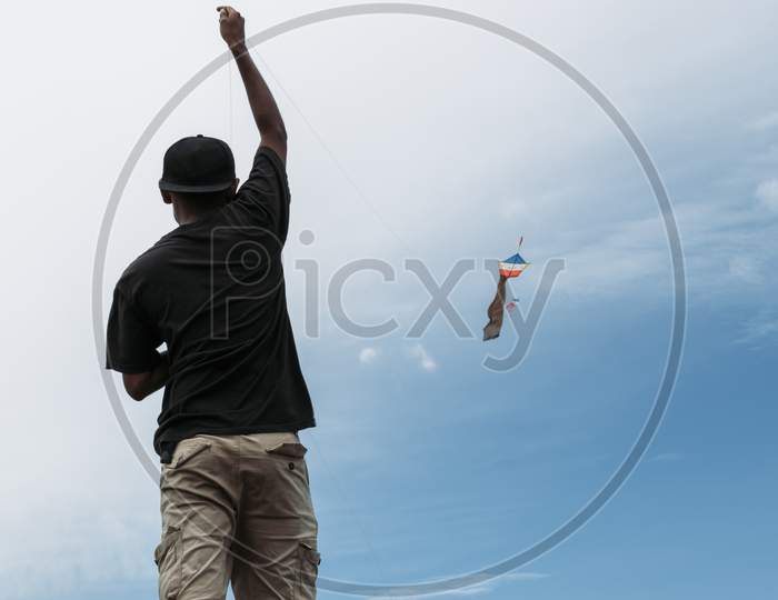 Photograph Of A Young Boy Flying A Kite On A River Bank