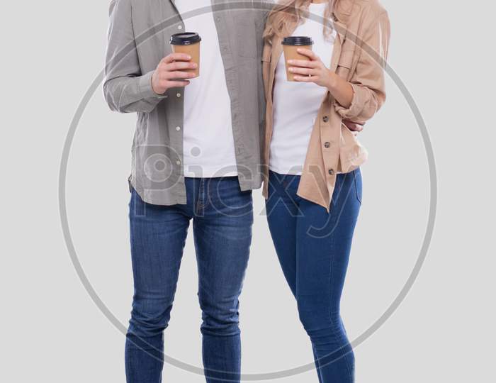 Couple Holding Coffee Cups Looking At Each Other Isolated. Couple Standing And Holding Coffee To Go Cup. Man And Woman Hugging, Lovers, Friends, Couple Concept.