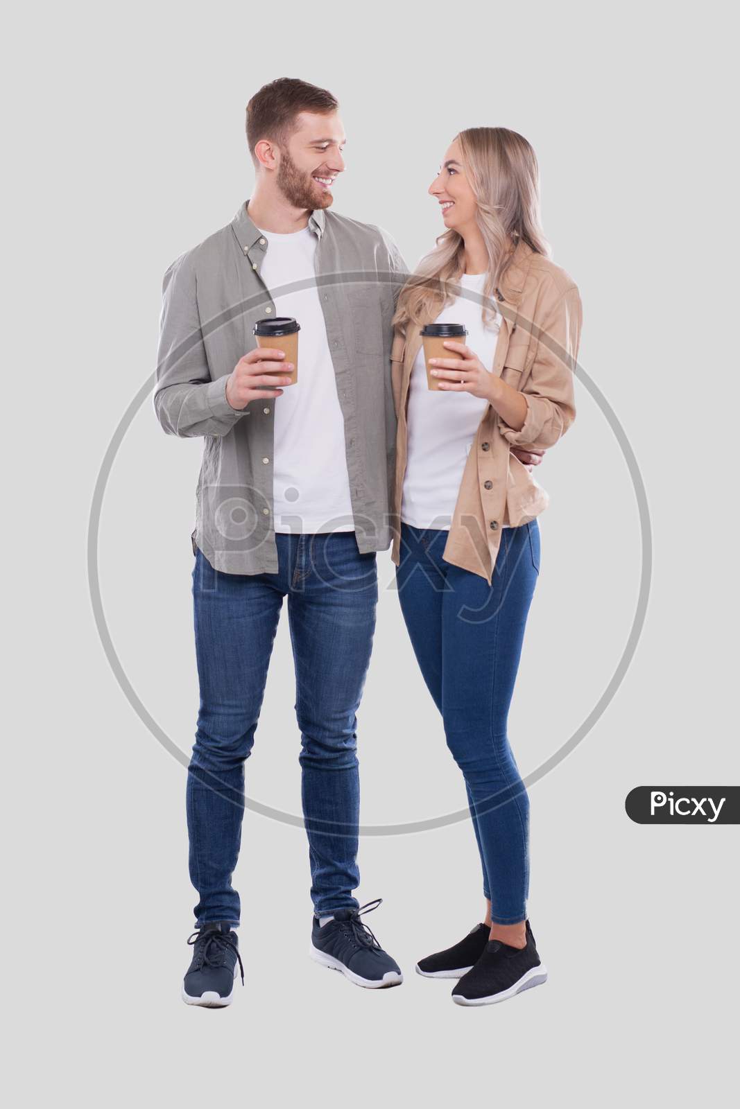 Couple Holding Coffee Cups Looking At Each Other Isolated. Couple Standing And Holding Coffee To Go Cup. Man And Woman Hugging, Lovers, Friends, Couple Concept.