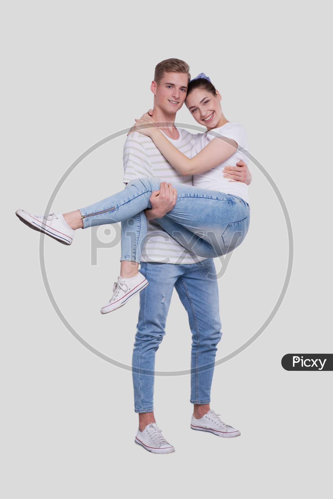 Man Holding Girl In His Arms. Couple Standing Isolated. Lovely Couple Looking To The Camera.