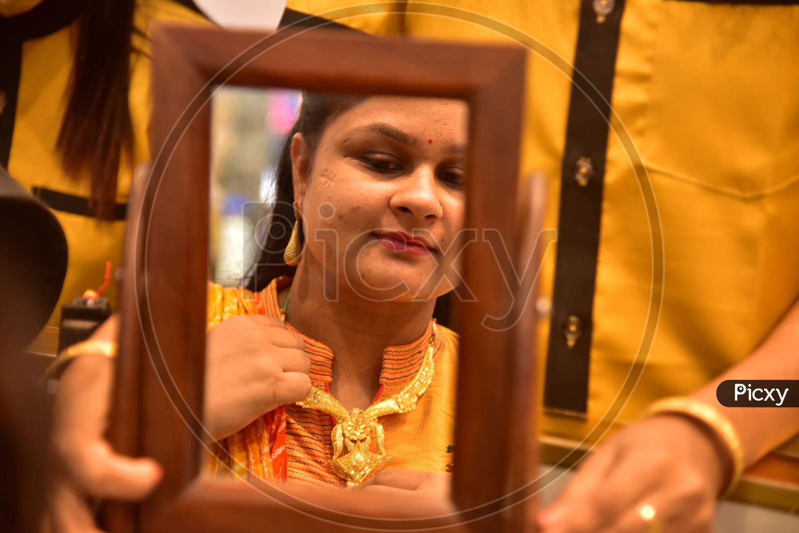 :A woman tries a gold ornaments  at a jewellery showroom during Dhanteras in Nagaon district, in the northeastern state of Assam on Nov 12,2020