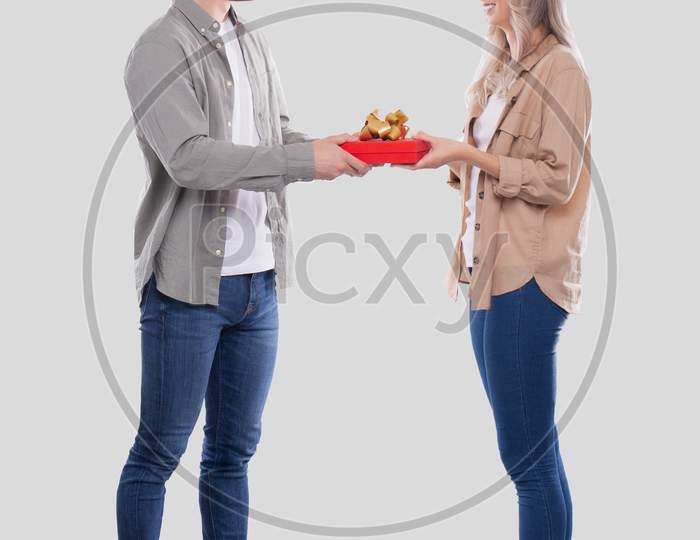 Couple Standing Looking At Each Other Holding Gift Isolated. Woman Suprised By Gift From Man. Man Making A Gift To Girl. Couple Day. Present For Girl