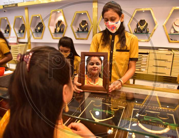 A woman tries a gold ornaments  at a jewellery showroom during Dhanteras in Nagaon district, in the northeastern state of Assam on Nov 12,2020