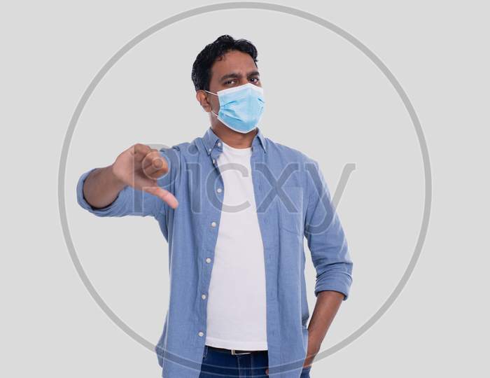 Indian Man Wearing Medical Mask Showing Thumb Down Isolated. Man In Blue Shirt With Medical Mask. Health, Virus, Medical Concept