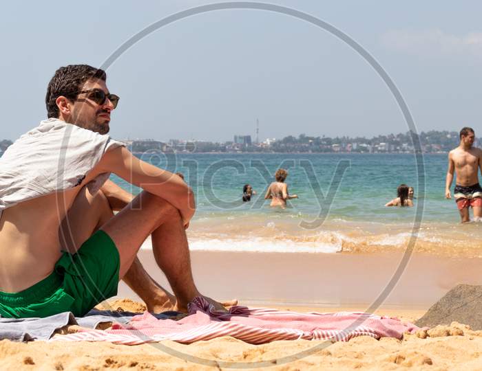 Young Male Sunbathing And Enjoying The View In The Picturesque Beach