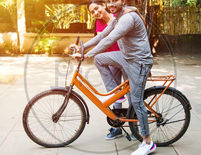 Asian Indian Young Couple Riding On Bicycle, Posing For A Photo