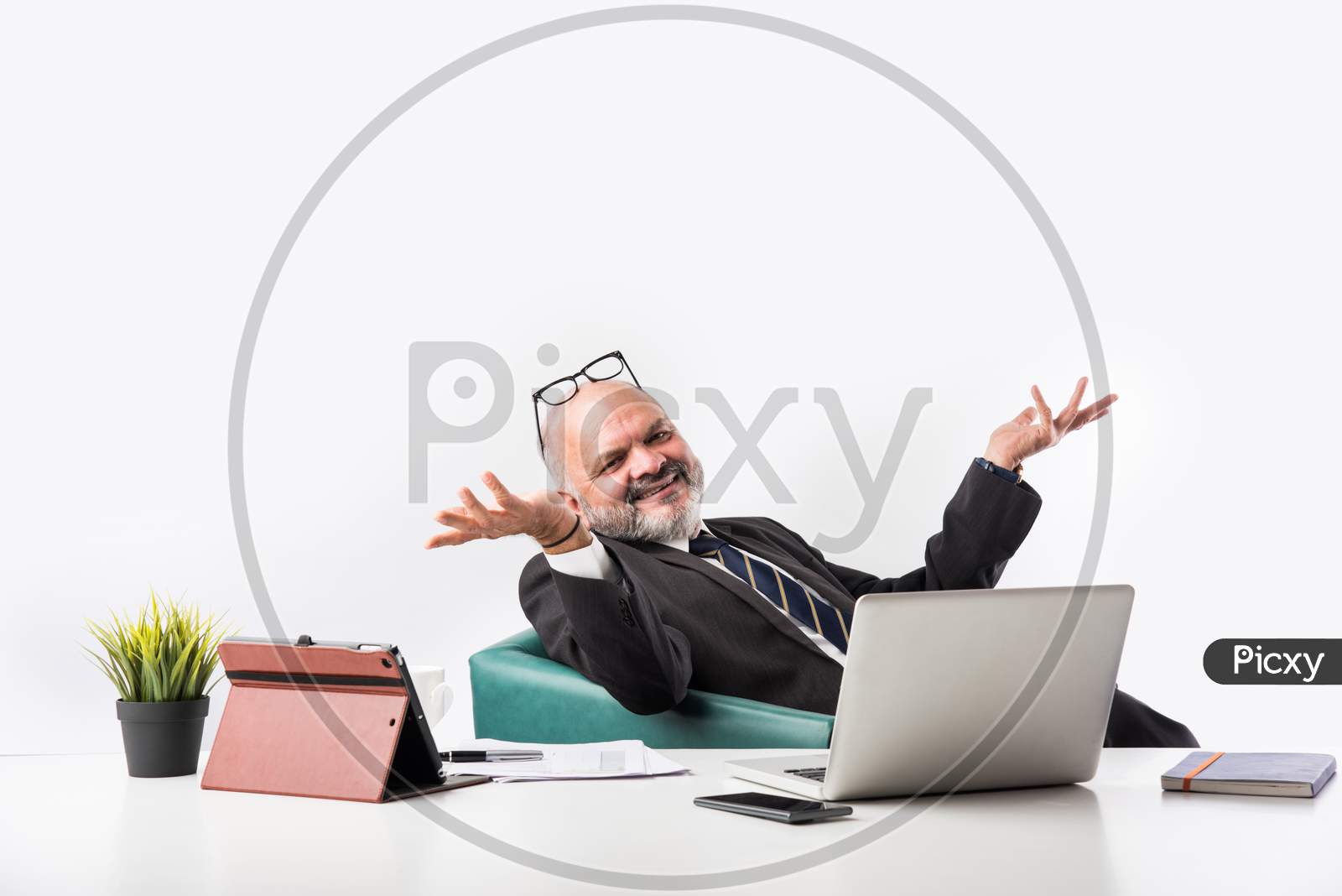 Mature Asian Indian Businessman Relaxing Or Resting In Armchair With Legs Up On Office Desk