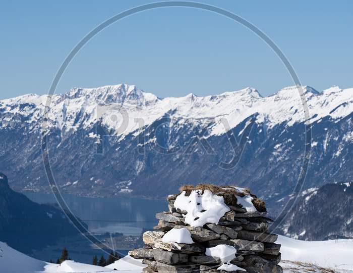 Stone Stack In Bernes Alps With Snow Caped Mountains And Brienzersee In Background.