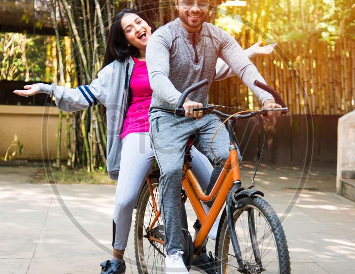 Asian Indian Young Couple Riding On Bicycle, Posing For A Photo