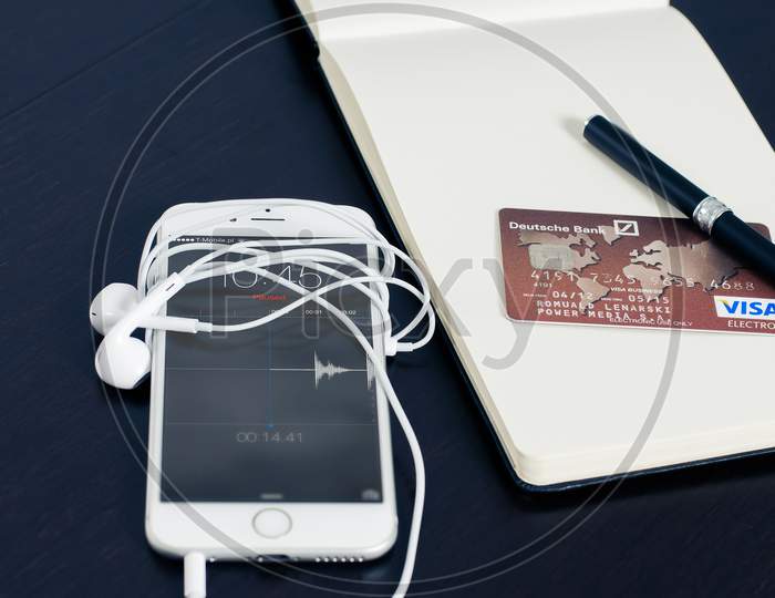 iPhone On Desk With Earphone , Credit Card & Pen