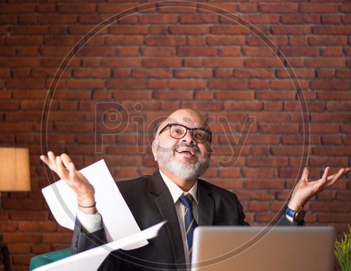 Indian Mature Businessman Reading Or Throwing Paper Documents