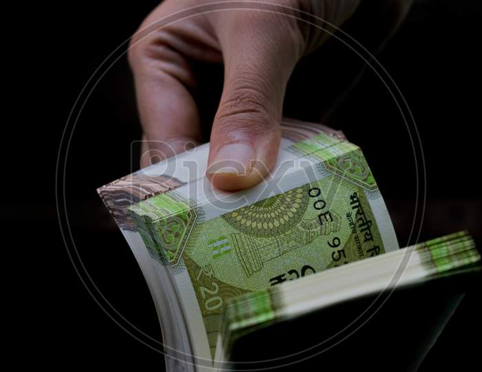 Indian woman hand counting the currency note bundle isolated on black.