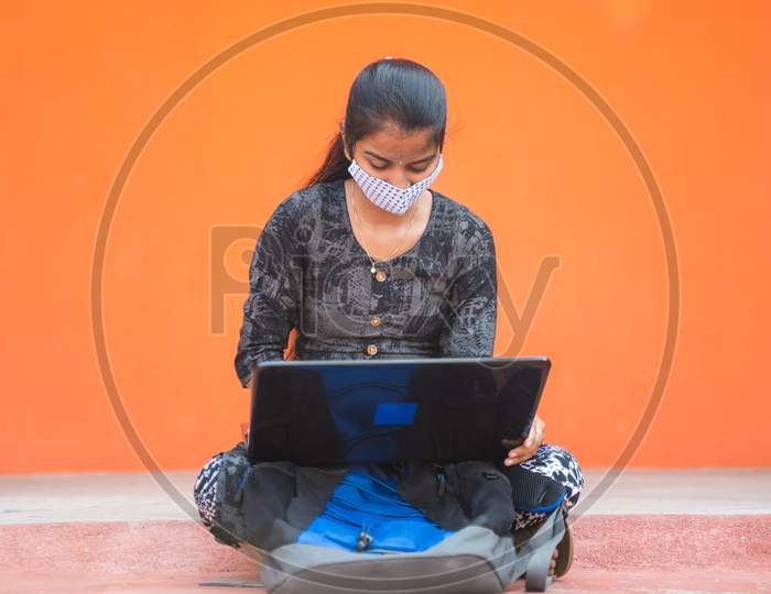 Young Girl Student In Medical Mask Busy Working On Laptop At Caollege Corridor Or Universtiy Campus - Concept Of College Reopen, New Normal Due To Coronavirus Or Covid-19 Pandemic.