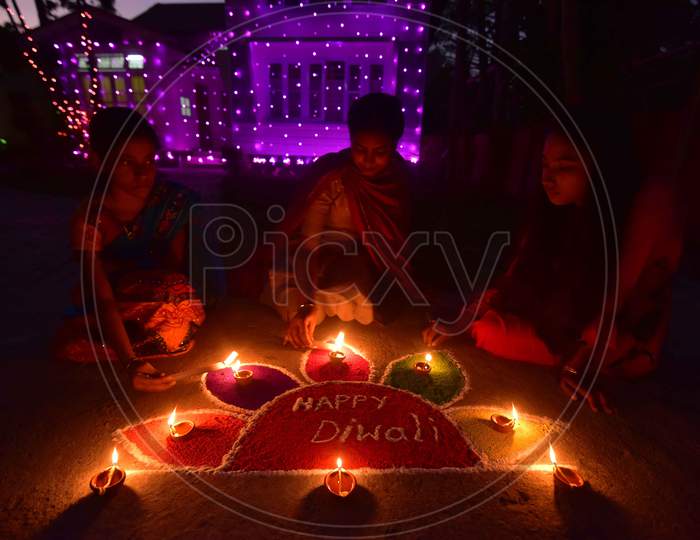 Girls pose after lighting oil lamps around a "Rangoli", a traditional pattern made from coloured powders and flower petals outside their home  to celebrate Diwali, the Hindu festival of lights, in Nagaon District of Assam,india  on Nov 14,2020.