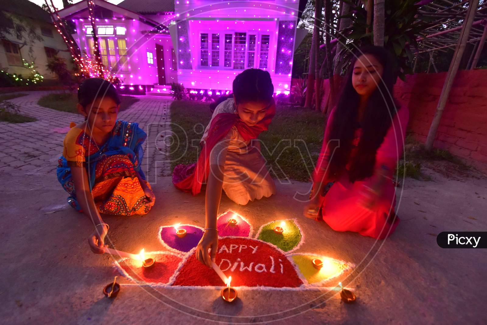 Girls pose after lighting oil lamps around a "Rangoli", a traditional pattern made from coloured powders and flower petals outside their home  to celebrate Diwali, the Hindu festival of lights, in Nagaon District of Assam,india  on Nov 14,2020.