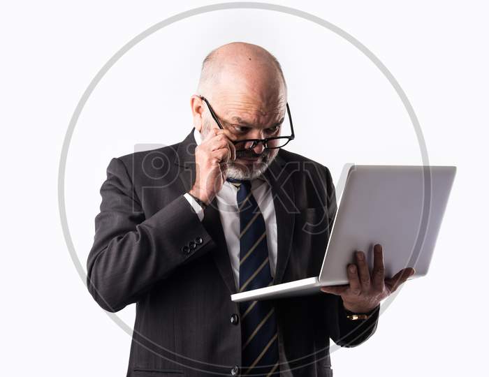 Indian Senior Businessman Using Or Presenting Laptop Computer, Tablet Or Speaking On Smart Phone