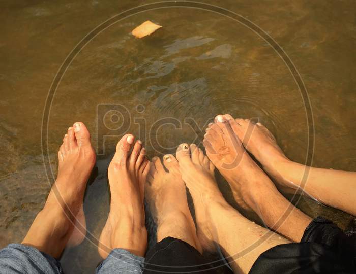 feet of family or group of friends on the water.many people sitting together on sand near the sea, summer holidays