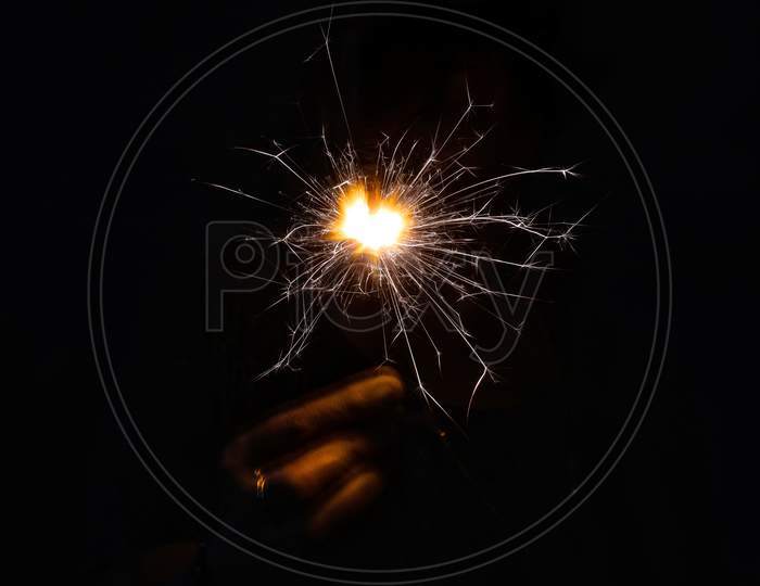 Person holding a sparkler against black background