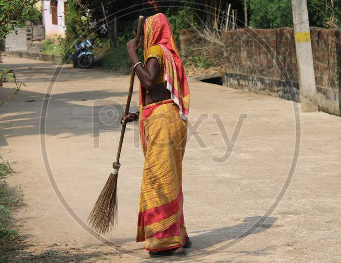Indian Women Sweeper Clean The Road On The Morning and hold the scrub brush.