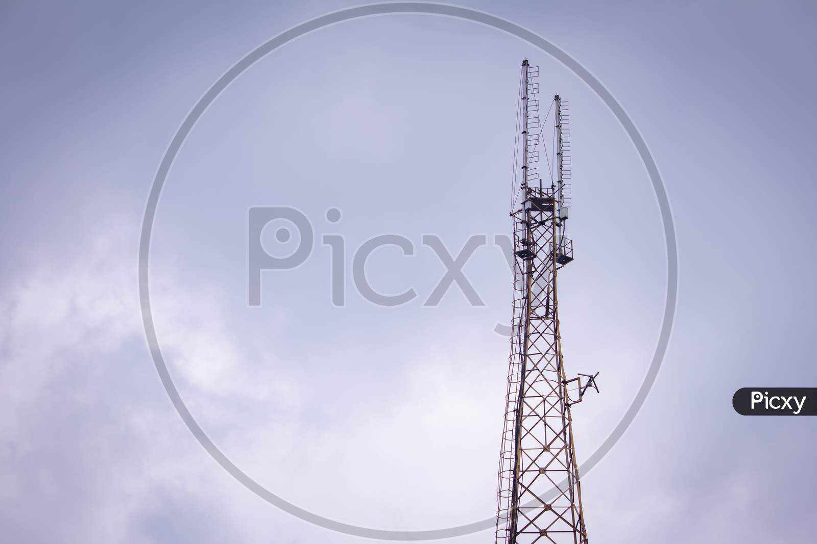 Communication Tower With The Overcast Sky Background.