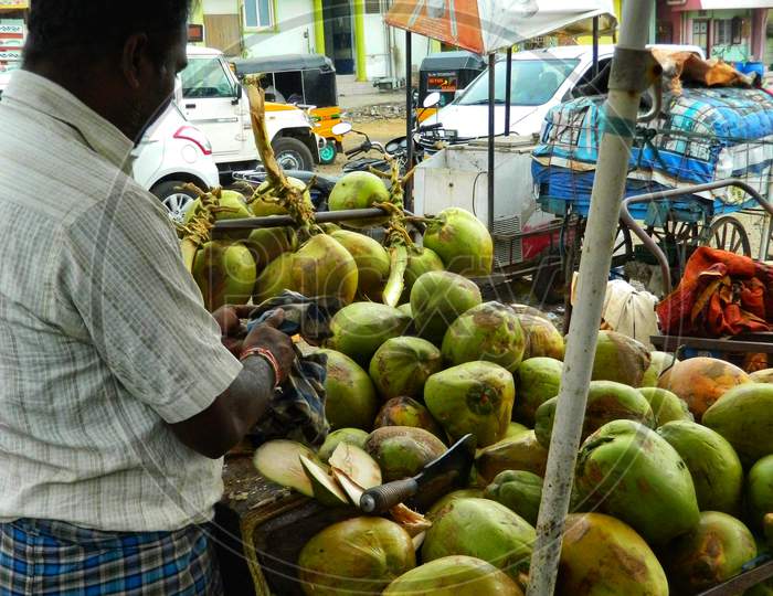 Shopkeeper cutting and selling coconut water