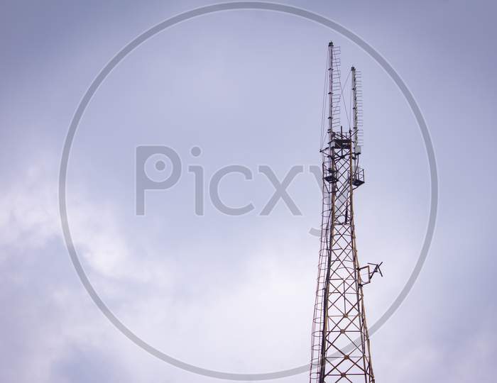 Communication Tower With The Overcast Sky Background.