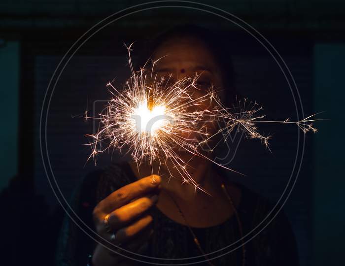 sparkler held by woman / person in her hands against black background