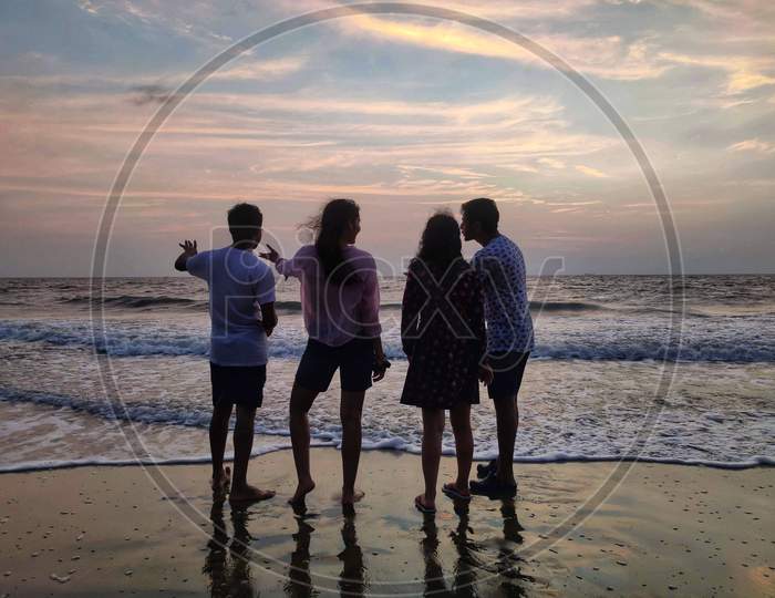Candid photo of random friends at sunset at beach as silhouette