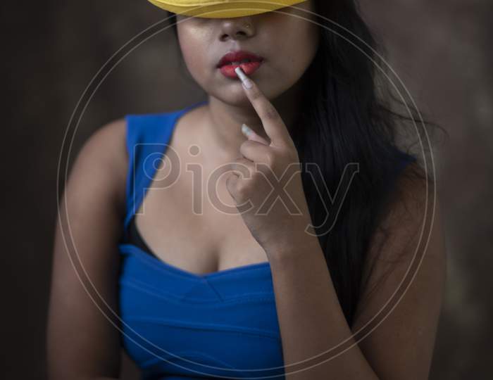 Studio Portrait Of An Young Indian Girl In Blue Western Dress And Yellow Hat In Front Of Textured Background. Fashion Portrait Photography