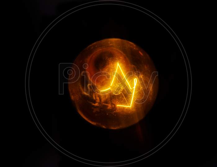 Golden yellow filament bulb isolated in black background