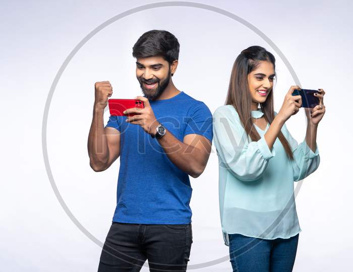 Indian Couple make happy gestures as they use Mobile Phones