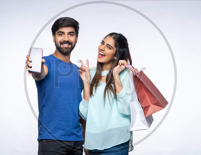 Young Indian Couple carrying colourful Shopping Bags