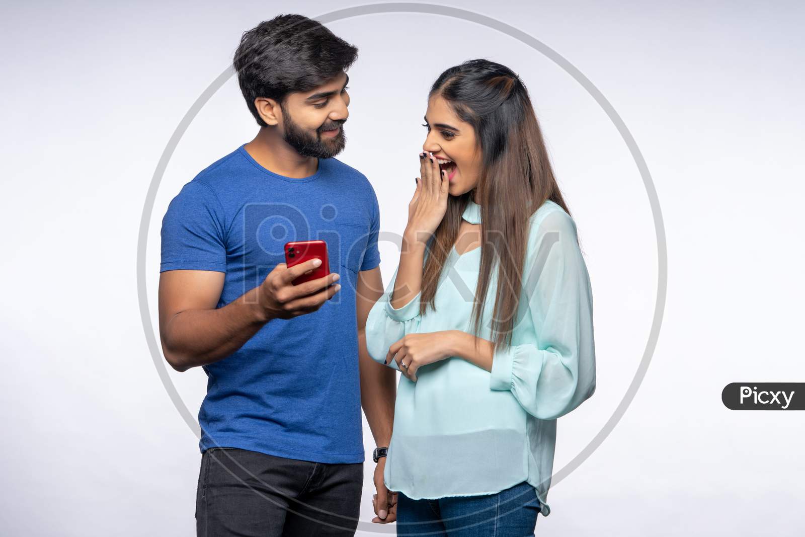 Happy Young Indian Couple making gestures while using a Smartphone.