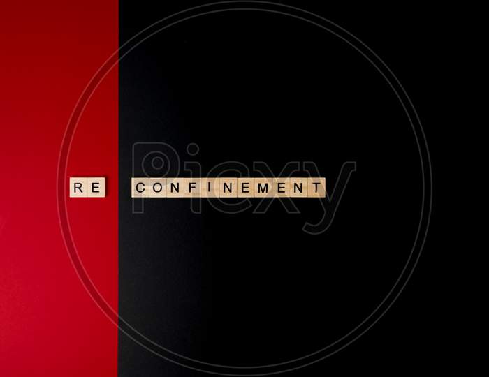 Wooden Letters On A Red And Black Background Forming The Word “Reconfinement”. Second Wave During Coronavirus Pandemic Concept.