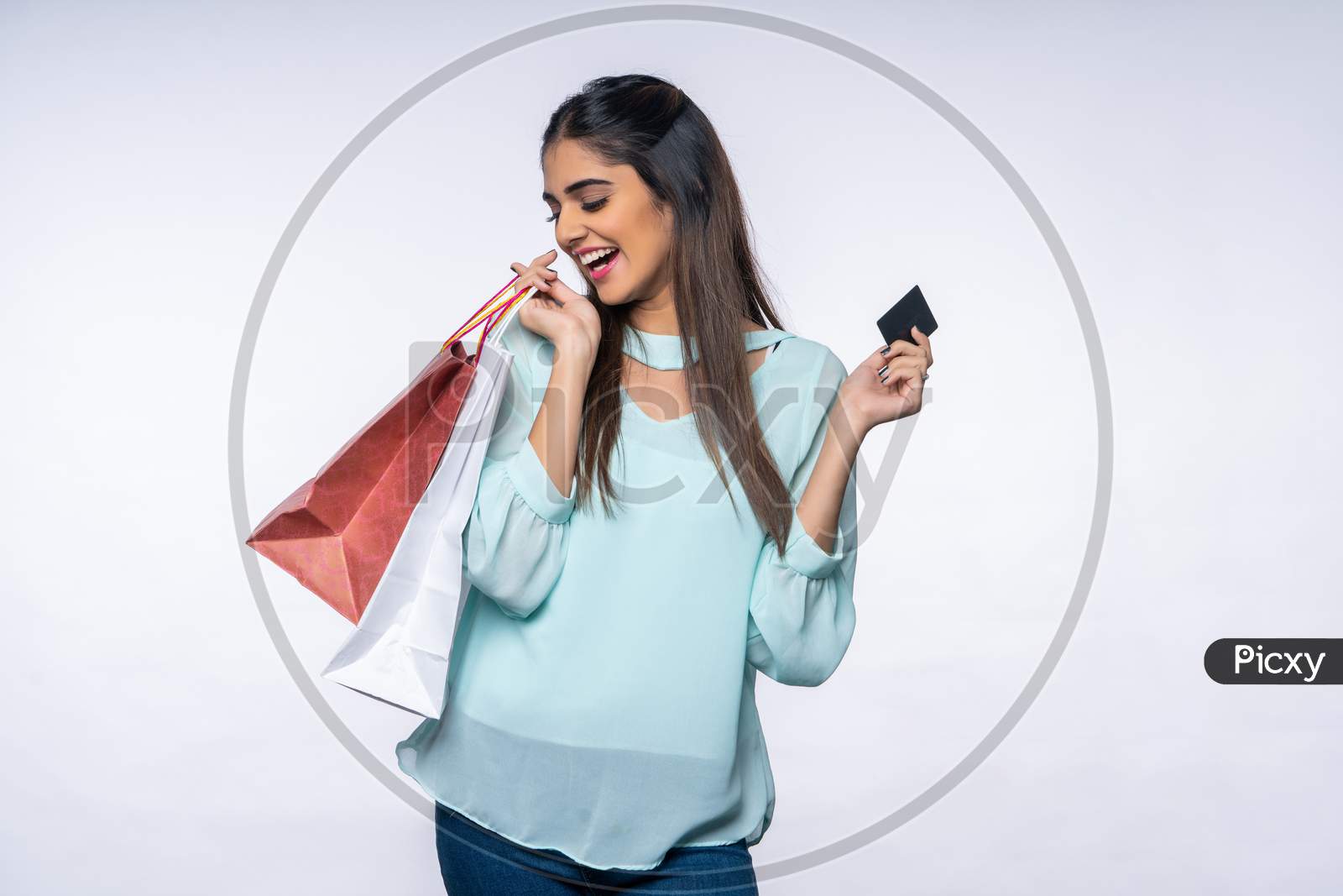 excited young Indian woman showing Card and Shopping bags