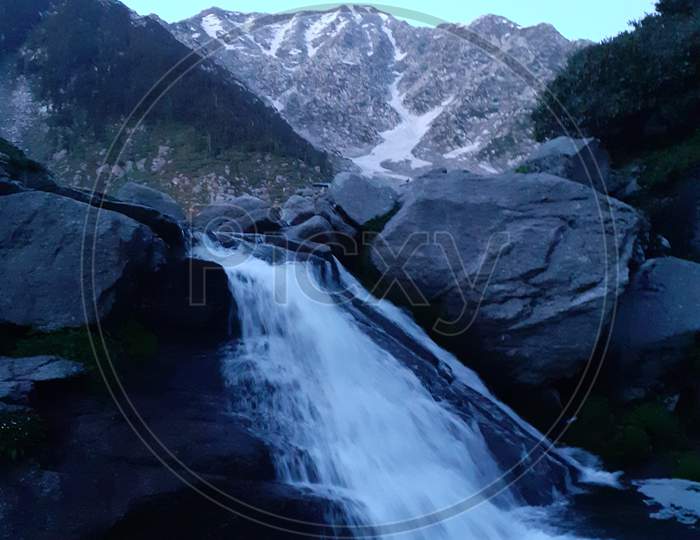 Fresh glacier water falls flowing under rocks of Minkiani pass
