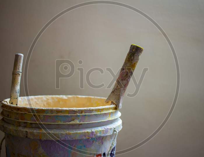 View Of A Paint Bucket And Brush Against Wall Background