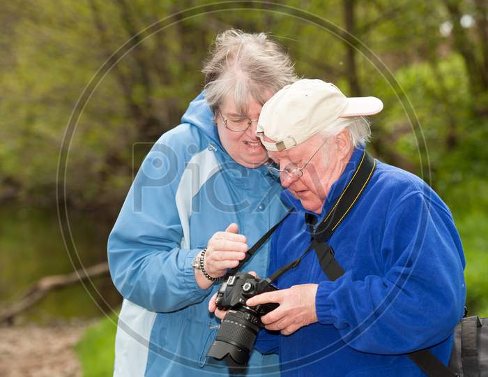Elderly Couple Review Photographs On The Back Of A Dslr Camera
