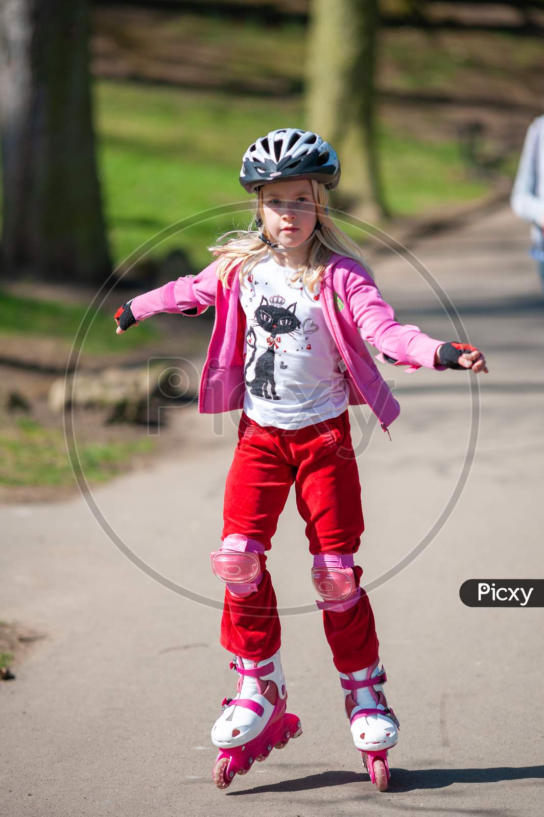 A Young Girl On Roller Blades Wearing Protective Equipment