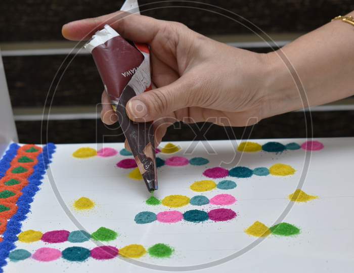 Woman Hand Making Rangoli Designs With Paper Cone Using Different Rangoli Colors On Door Entrance